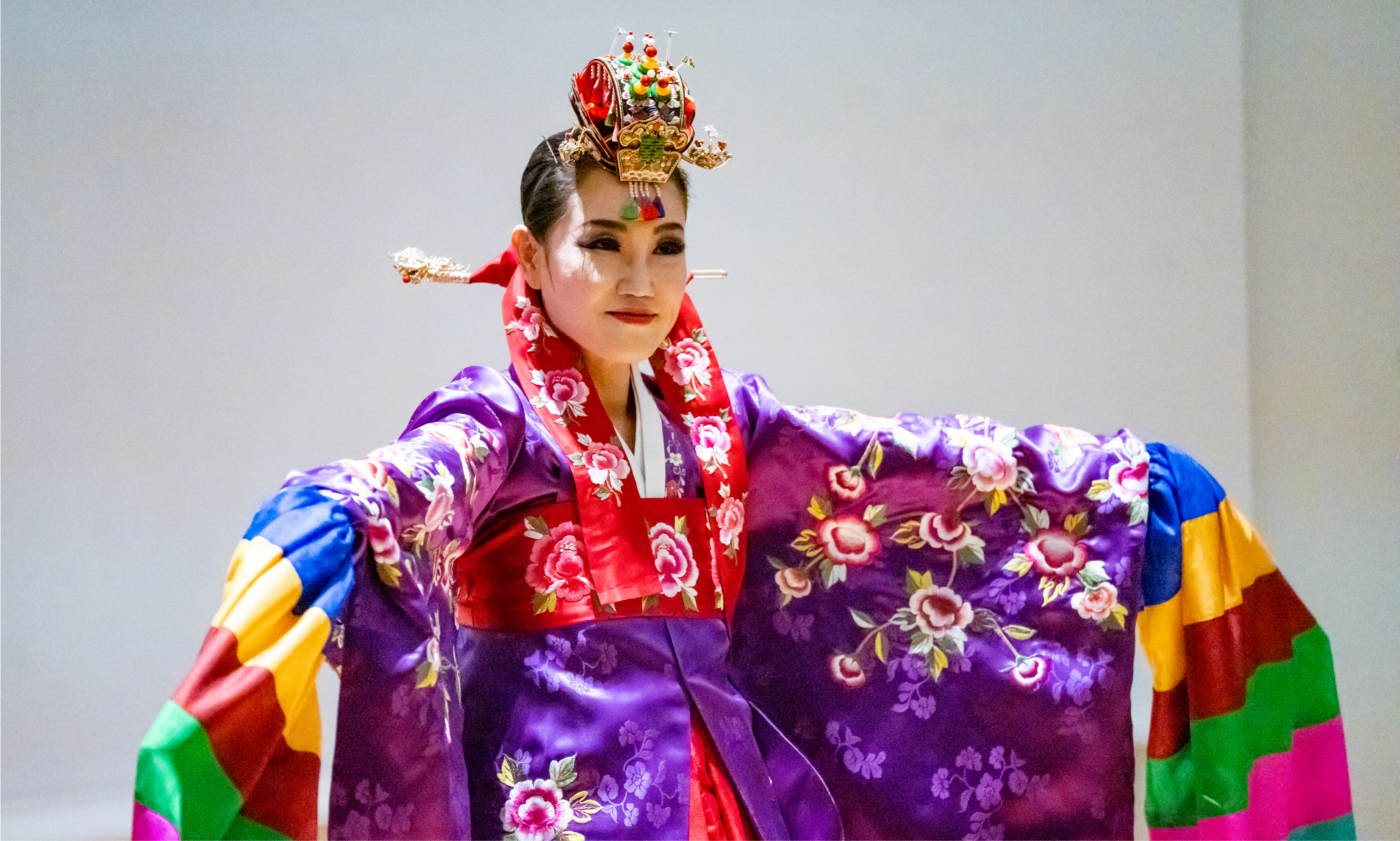 Kate Kim wears a brightly-colored hanbok and headdress while performing a traditional Korean prayer dance.