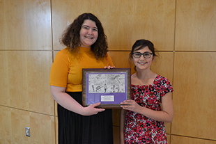 JMU Student Lydia Manson presents the award for best currency design, and award she, herself won as a middle school student