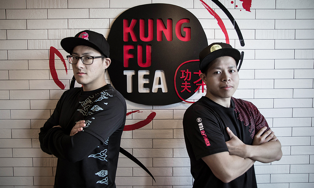 Michael Wu and Parter posing in front of the Kung Fu Tea logo