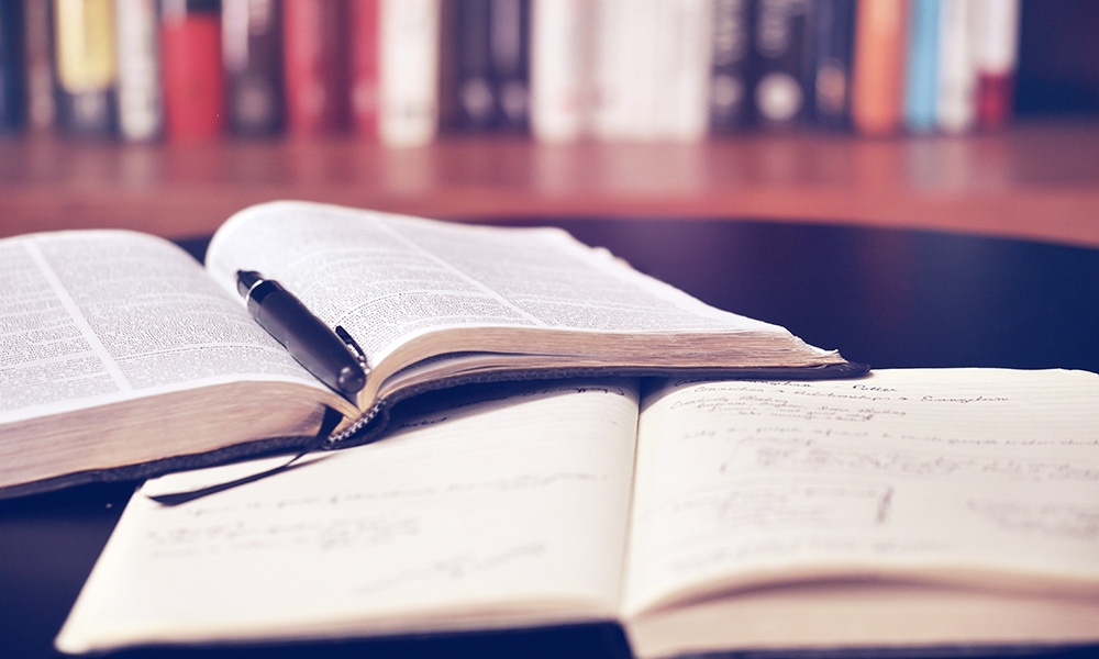 Stock image of an open book with pen lying on top of an open notebook