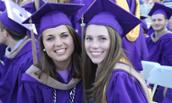 Two female students in cap and gown at CoB Graduation May 2015