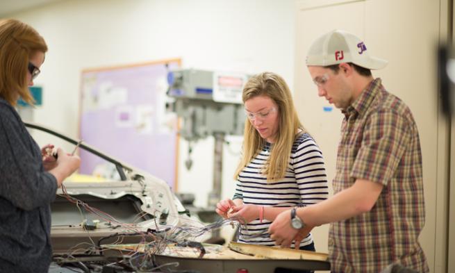 Students work on a car door