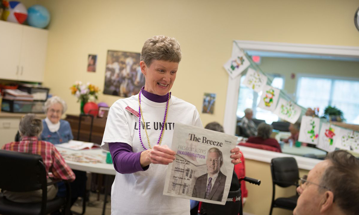 Generations Crossing director of adult programs, Lolley Miller, holds up a copy of the Breeze during a JMU Trivia game. One of the participants yelled out "He's nice looking!"
