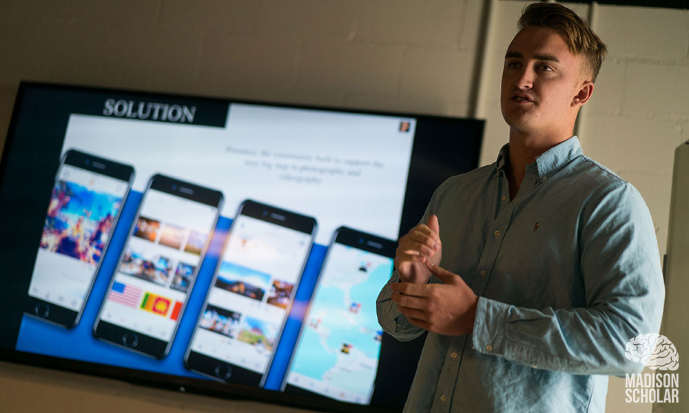 A member of the presence team discusses the project in front of screen with details of the project.