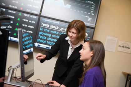 Mary Gowan helps a female student navigate a Bloomberg business computer terminal at JMU's College of Business