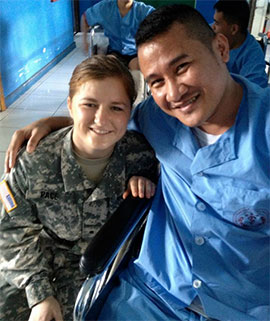 ROTC Cadet Erin Pace kneels beside a Philippines Military Medical Center patient