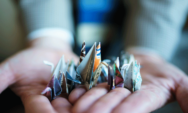 Photo of hands holding origami cranes