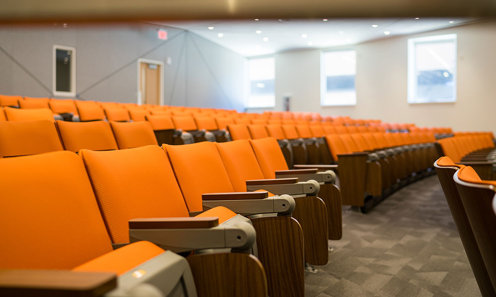 Rows of empty orange seats in one of the large lecture halls