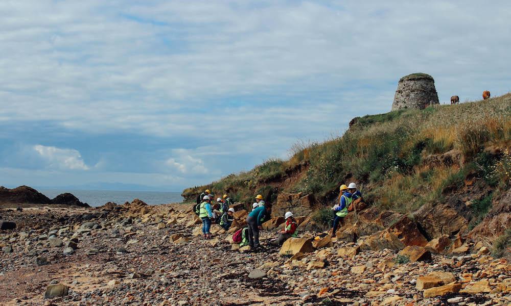 Students wearing hardhats examine a Scottish shoreline during a field experience