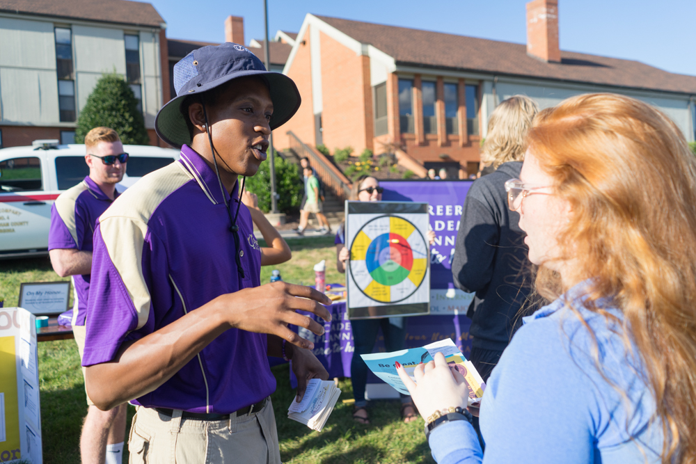 Two students talking outdoors at an informational booth. 