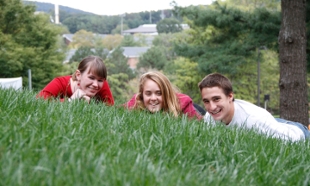 Three Eco Learning Community students laying in grass smiling