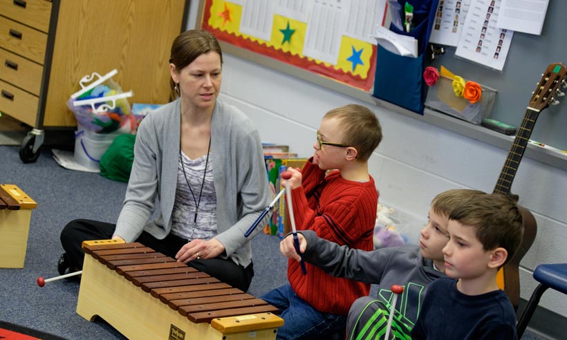 A student teacher works with children in a music class