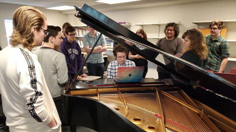 Students huddled around a piano