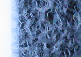 Close-up of soap bubbles inside a 2-liter bottle next to a light table.