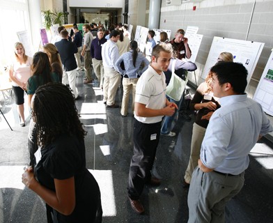 crowded hallway with posters and student presenters.