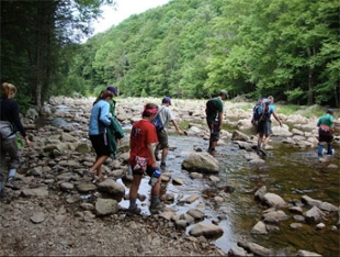 students on adventure trip cross a creek