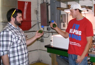 Student researchers hold beakers with algae water
