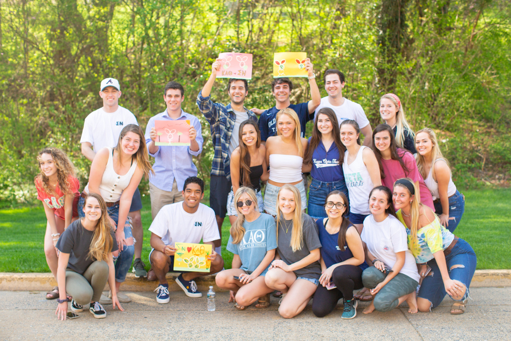 Members of various fraternities and sororities pose and smile together during the Egg Hunt on the Row event