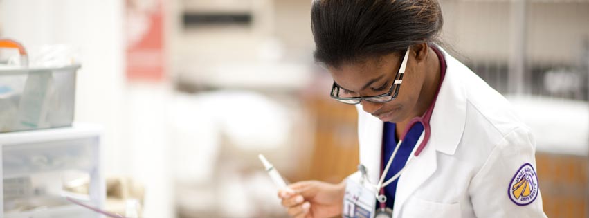 A student participates in a nursing simulation using a lifelike mannequin