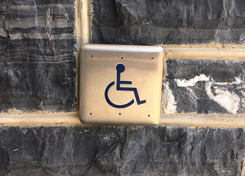 Accessible door opener plate against a stone wall.