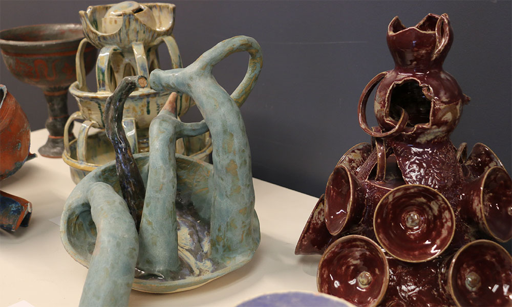 Several ceramic sculptures arranged on a table in the ceramics wing