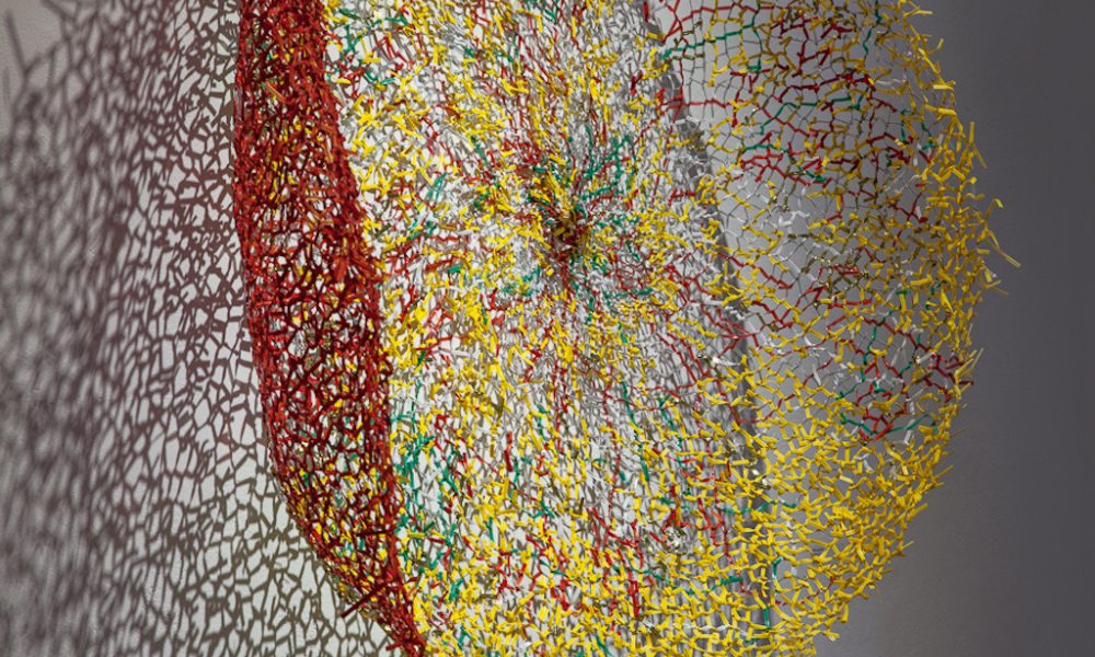 Red and yellow sphere constructed of textiles mounted on the wall