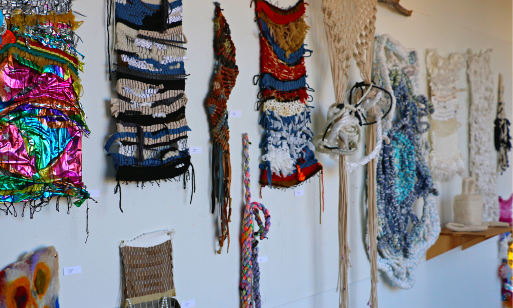 A display of weavings and other fibers projects