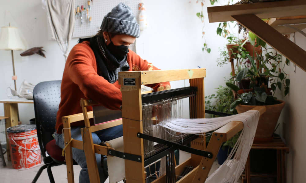 Mia Greenwald works on the loom in their studio