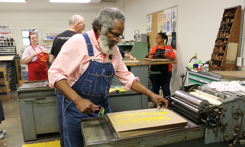 Amos Paul Kennedy, Jr. prints in the studio center with Harrisonburg High School students