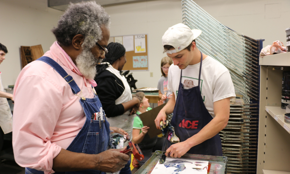 Amos Paul Kennedy, Jr. works with a student on his print.