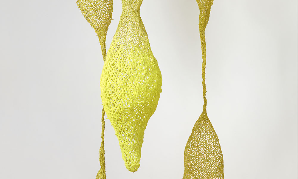 Three bulbous yellow sculptures hang from the ceiling.