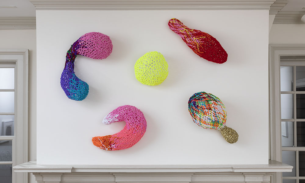 Five bulbous structures made of multicolored twist ties and pipe cleaners. 