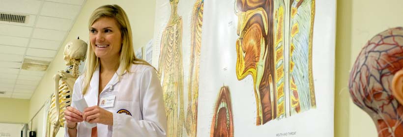 An instructor stands in front on anatomy posters and models