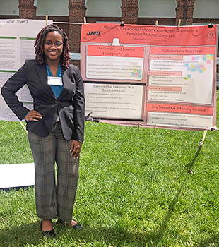 Cheyenne Sewell stands next to a red poster displayed on an easel outdoors.