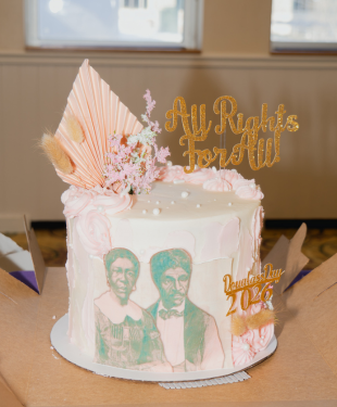 A cake with an image of Douglass and his spouse, as well as other flourishes. Skewers hold text saying "All Rights For All!" and "Douglass Day 2026"