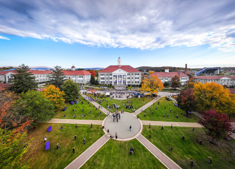 An aerial overview of JMU's iconic quad, filled with members of the marching band practicing for a homecoming performance.