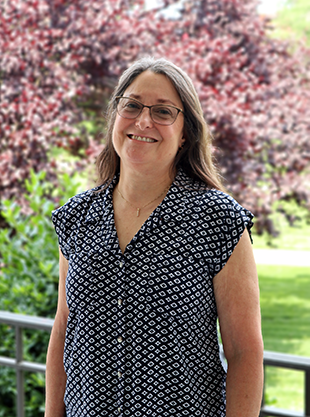 Dianne Fulk stands in front of trees.