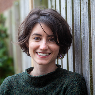 A portrait of Olivia Booker, leaning against a weathered wooden fence.