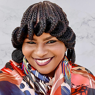 A portrait of Tiajuana L. Tillman, smiling widely in professional wear with a coiled hairstyle.