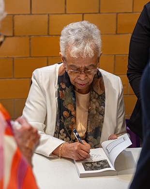 Ruth Toliver signing a book for a symposium attendee. 