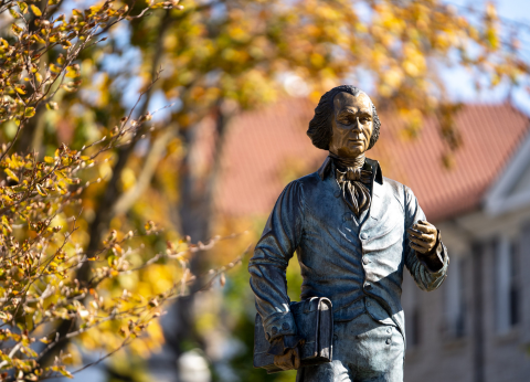 The iconic statue of Jimmy Madison on JMU's quad, surrounded by fall foliage.