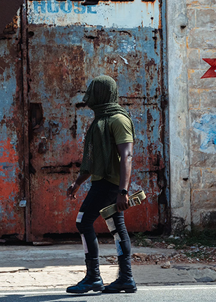 An African man walks on a street, his head covered by fabric.