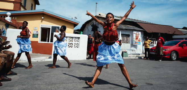 Children dancing in streets wearing colorful clothing.