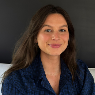 A woman with dark brown hair wearing a dark blue button-up shirt.