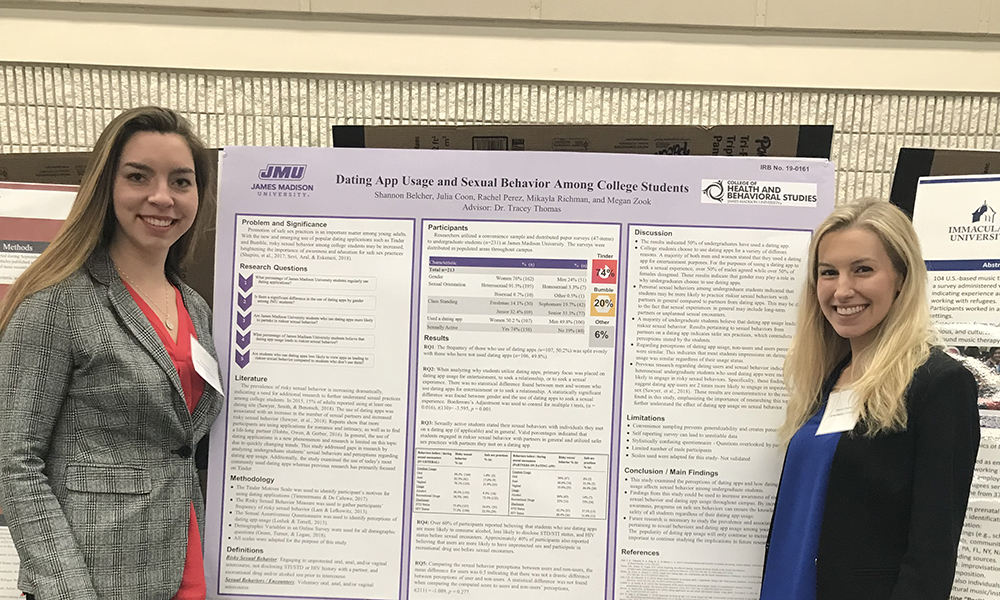 Graduate students in front of a poster describing their research project