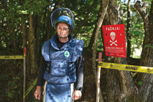 Male NPA deminer in Bosnia and Herzegovina wearing aramid body armor and a ballistic helmet with a polycarbonate visor.