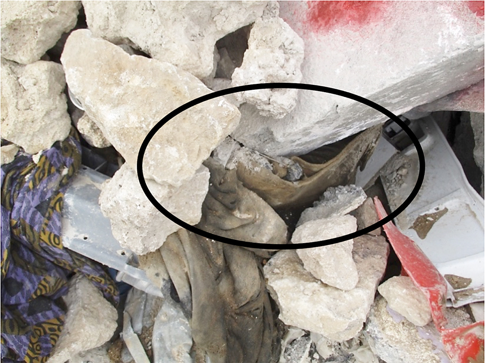 Figure 4. The push button switch (in circle) of a suicide vest associated with human remains sits in precarious rubble, Mosul, Iraq, 2017. The clearance of human remains and the presence of IEDs and switches in urban areas underline the need for HMA and HFA to develop ways to work effectively together. Image courtesy of Gareth Collett.