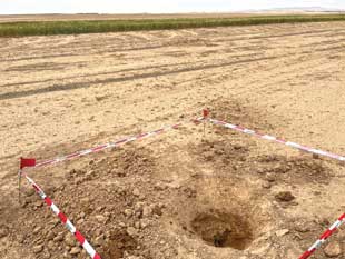 An explosive item identified in a former agricultural field in immediate proximity to cultivated land.  Image courtesy of ITF. 