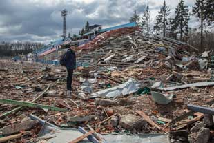A man stands in a small stadium in Ukraine that has been destroyed by Russian bombing
