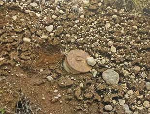 Possibly unexploded shell  largely buried in the sift soil.  Seen northwest of Gun A,  six-inch gun battery, North Head.  Image courtesy of the author/ Museum of the Aleutians. 